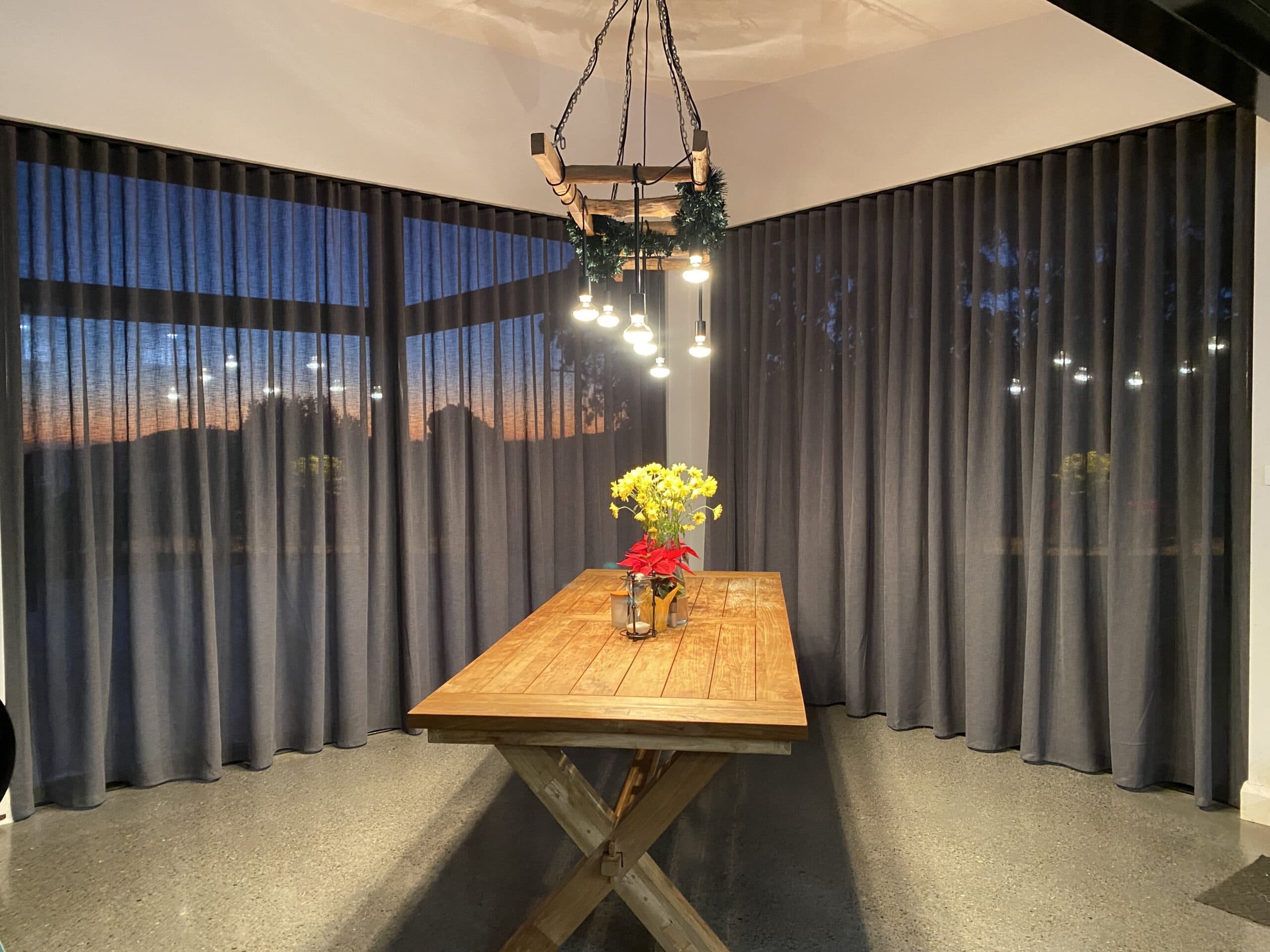 Charcoal S-fold sheer curtains around a dining room at dusk