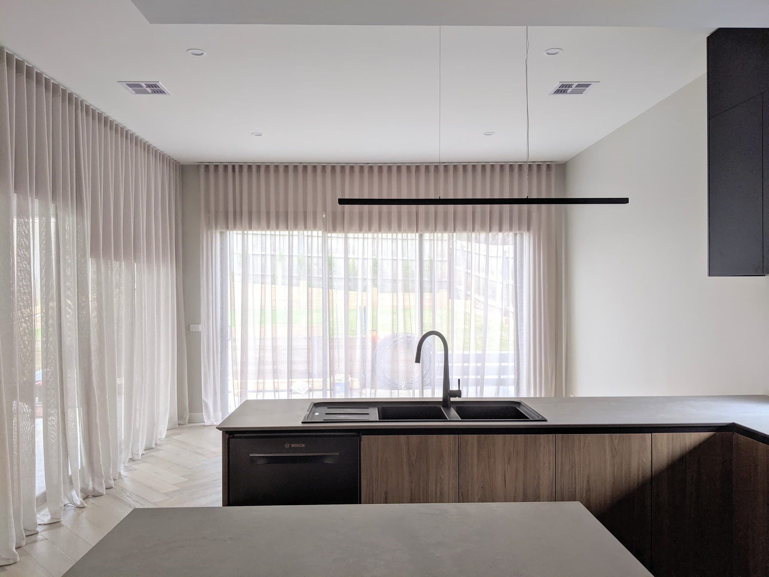 White S-fold sheer curtains across a kitchen and living area