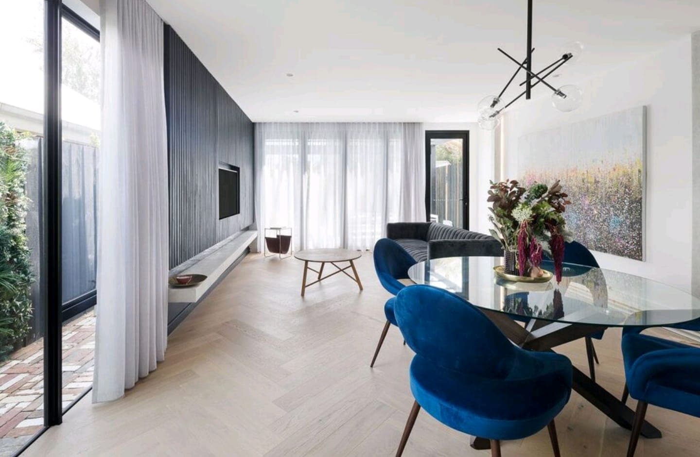 Sheer curtains in a dining room with blue velvet chairs