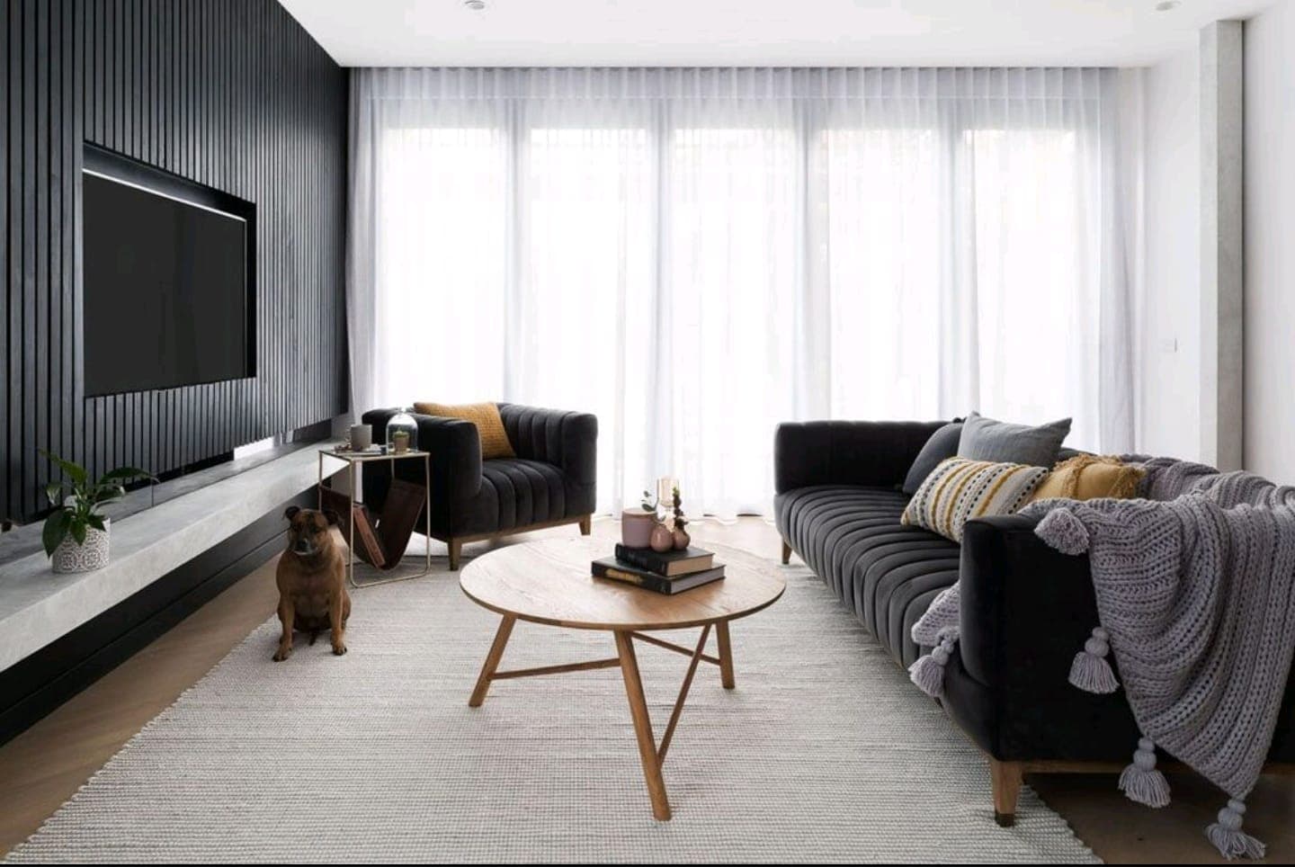 Linen look sheer curtains on a wide window behind a dark sofa