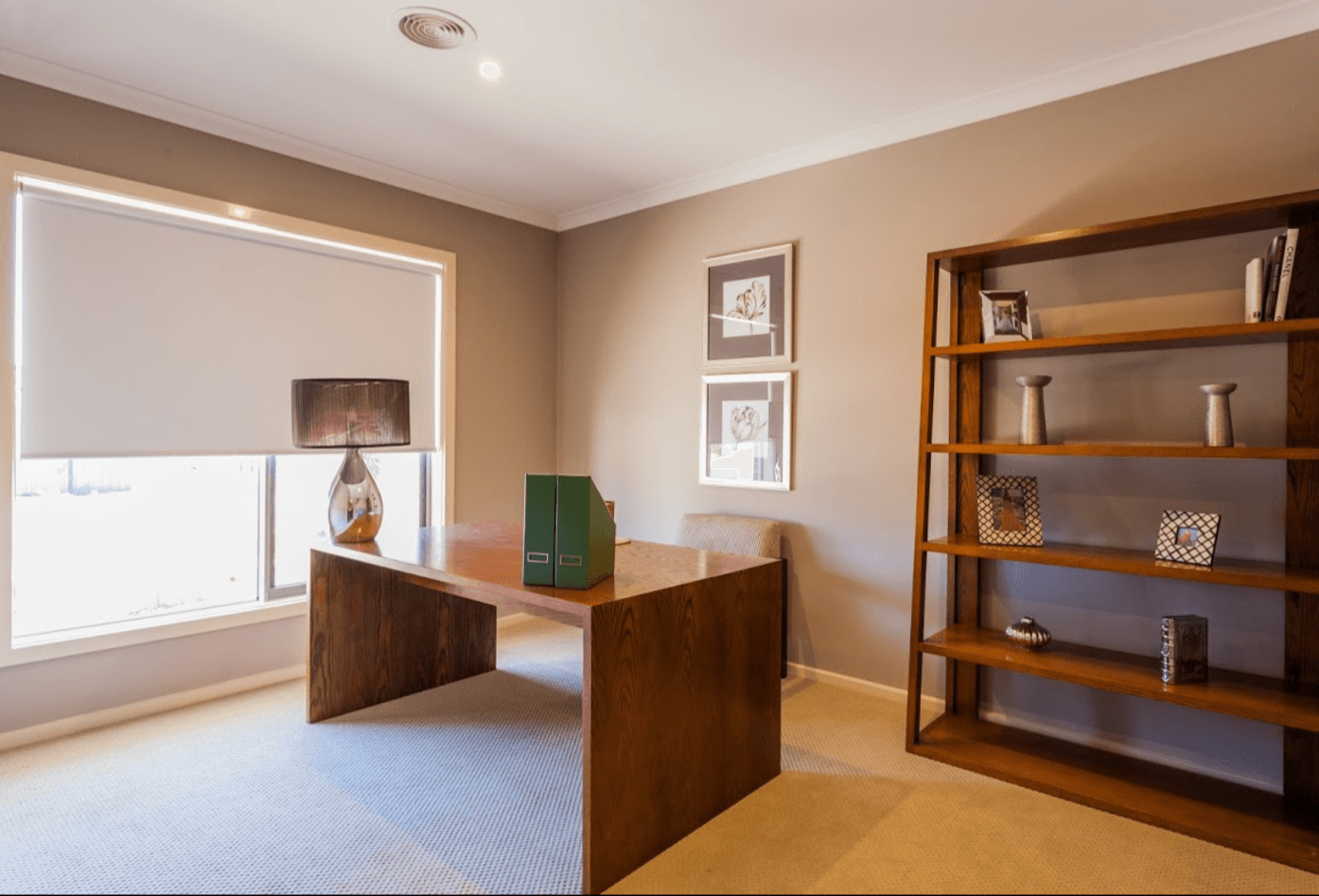 White blockout roller blind half lowered in a home office with a timber desk