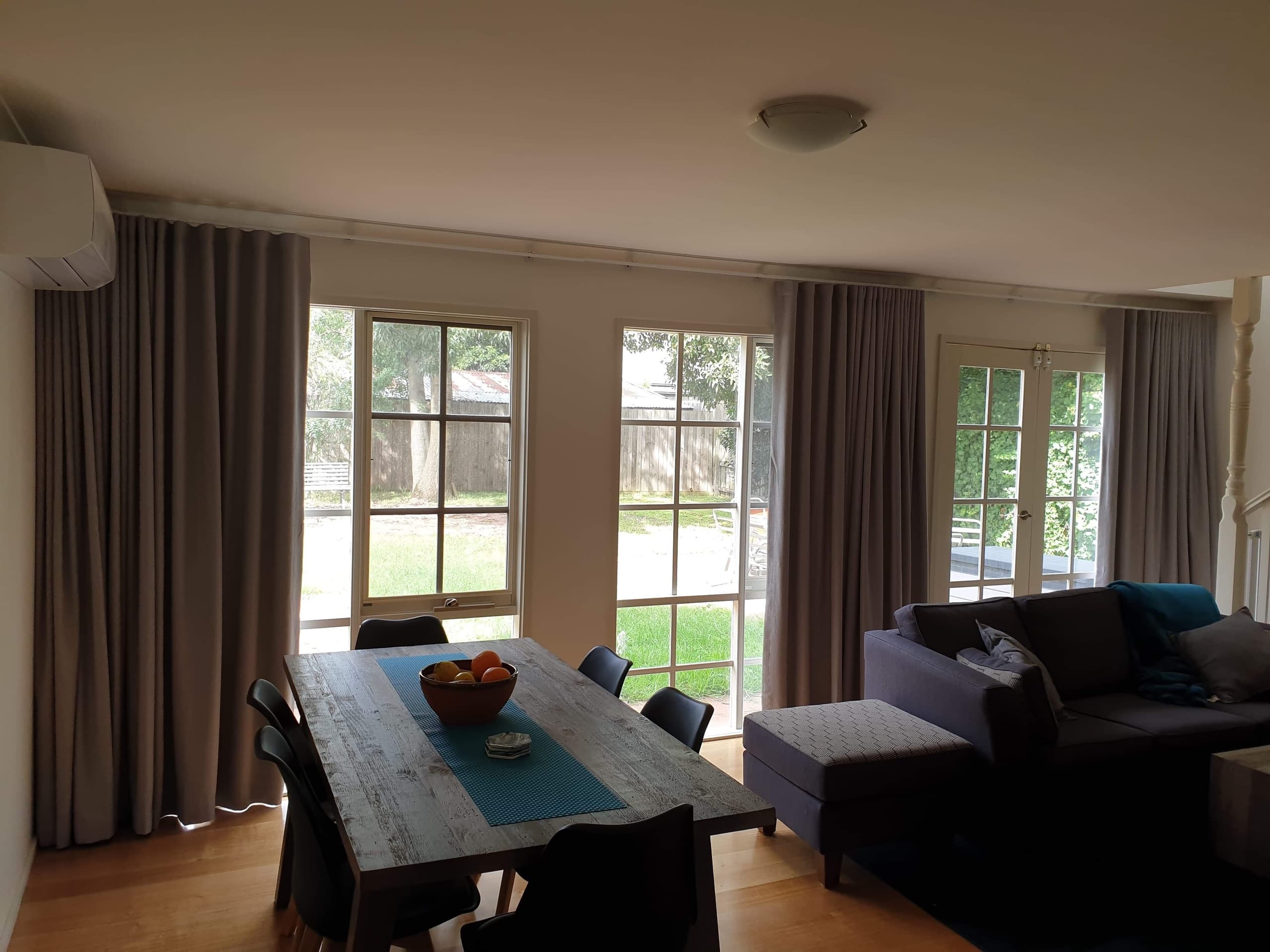 Grey lined curtains across a wall of windows behind a dining table