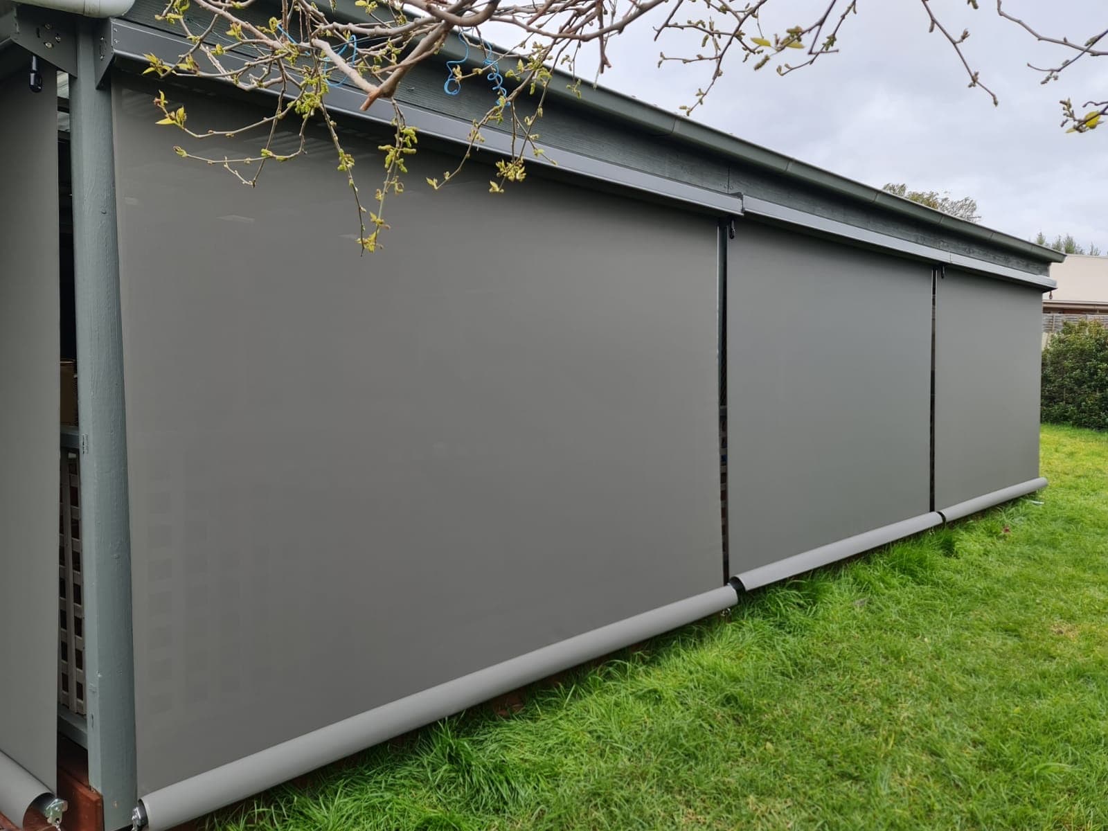 Grey outdoor blinds fully lowered around a pergola